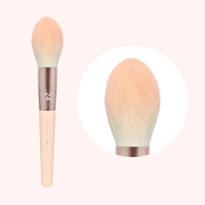 A makeup brush with a light pink handle and beige brush head, labeled with &