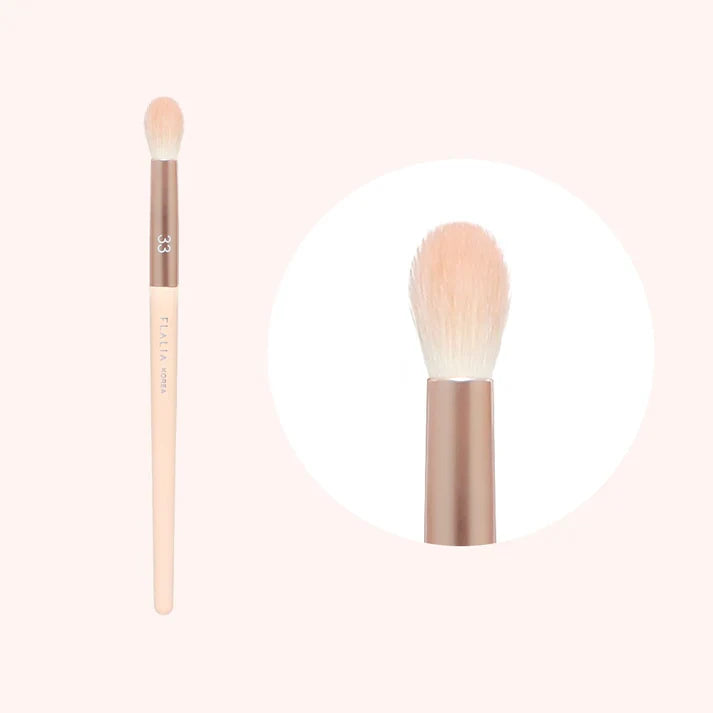 A makeup brush with a flat, round head with beige bristles and a beige handle.