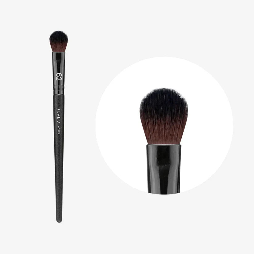 A makeup brush with a flat, round shadow brush head, predominantly black in color with a brand logo visible on the handle.